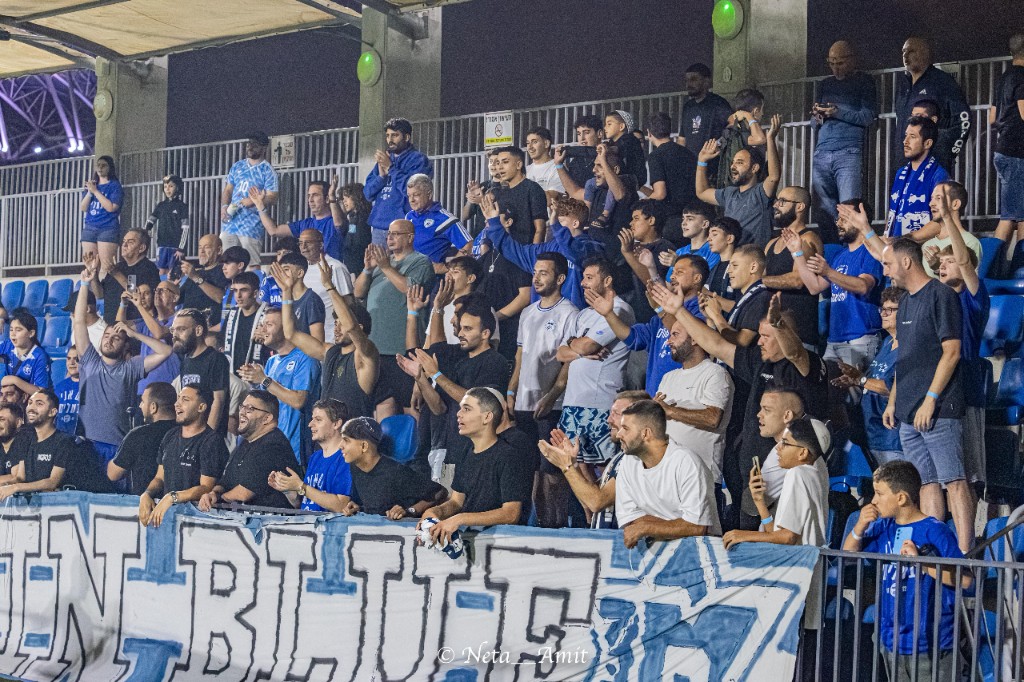 אוהדים חוגגים ביציע עם באנר Men in Blue